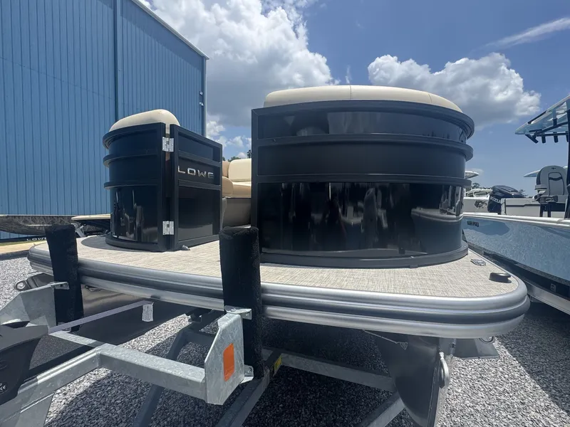 Slide: The Image of A 2026 Lowe LS Walk Thru 210 pontoon boat on a trailer, in front of a blue building. - 3