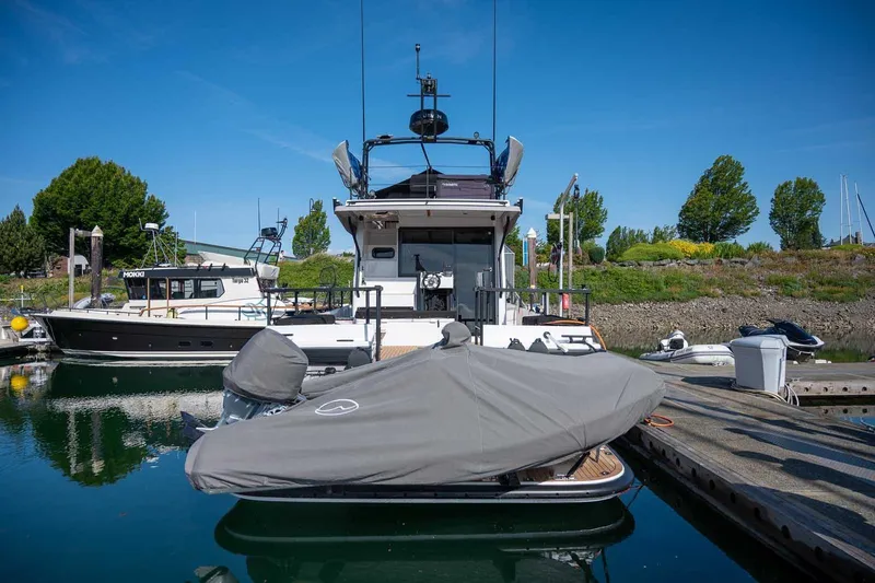 Slide: The Image of 2025 Targa 46 yacht docked at marina, covered boat in foreground, clear blue sky. - 3