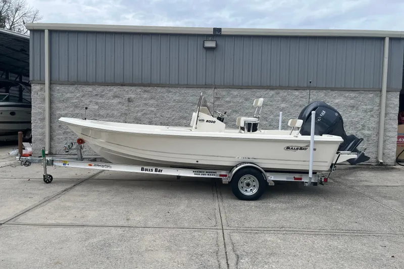 The Image of 2026 Bulls Bay 2000 boat on trailer, parked outside a metal building. - 1