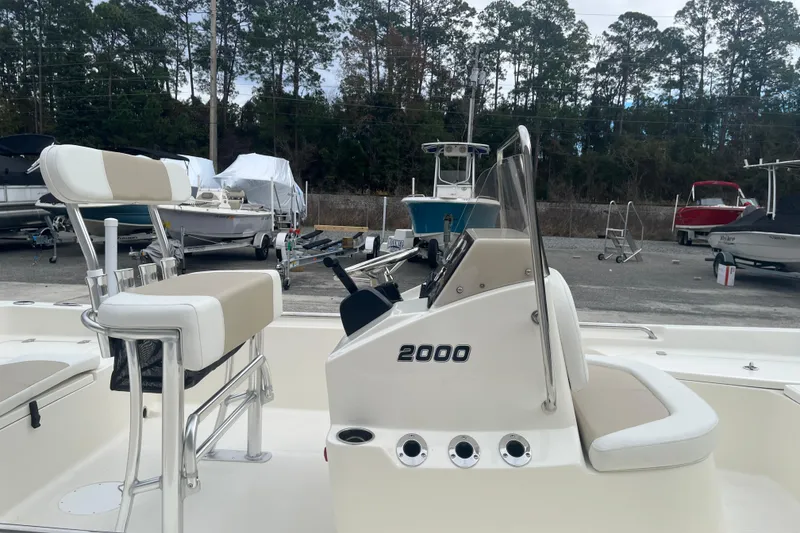 Slide: The Image of 2026 Bulls Bay 2000 boat with seating and console, parked outdoors with other boats. - 10