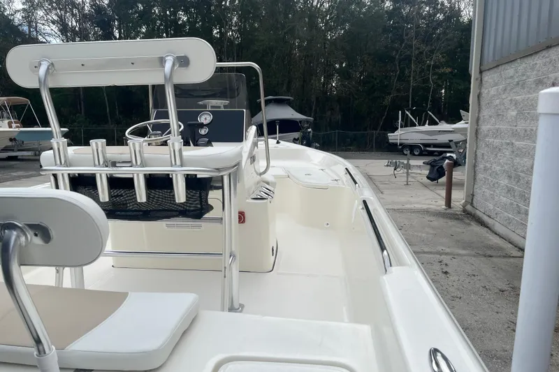 Slide: The Image of 2026 Bulls Bay 2000 boat interior with seating and rod holders, parked outdoors. - 12