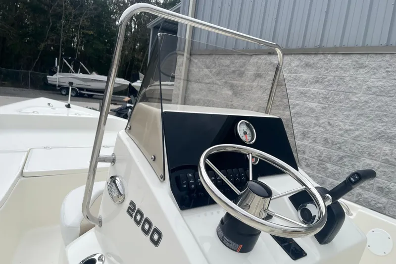 Slide: The Image of 2026 Bulls Bay 2000 boat console with steering wheel and controls, docked near a building. - 16
