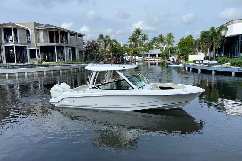 Slide: The Image of 2021 Boston Whaler 280 Vantage boat on a calm canal with modern homes. - 2