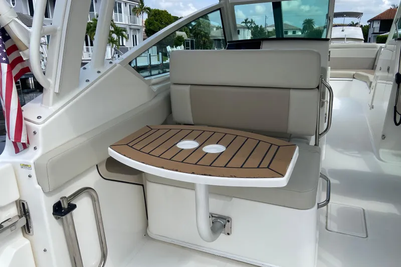 Slide: The Image of 2021 Boston Whaler 280 Vantage interior with seating and table, docked near waterfront homes. - 25
