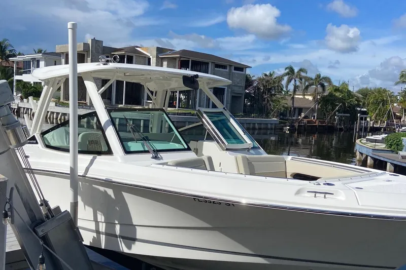 Slide: The Image of 2021 Boston Whaler 280 Vantage boat docked by waterfront homes under a blue sky. - 40