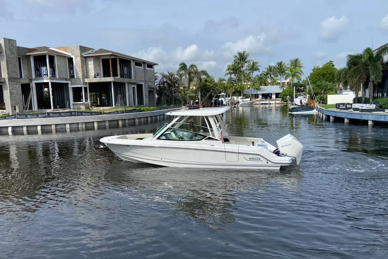 Slide: The Image of 2021 Boston Whaler 280 Vantage cruising in a scenic canal with modern homes. - 5