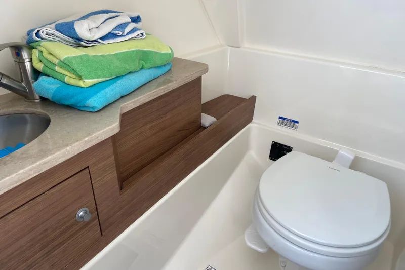 Slide: The Image of 2021 Boston Whaler 280 Vantage boat bathroom with sink, toilet, and colorful towels. - 9