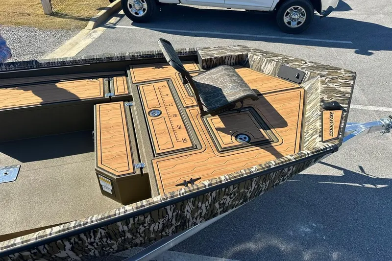 Slide: The Image of 2026 Avid 18 Commander boat with camo design and wood-patterned deck in parking lot. - 12