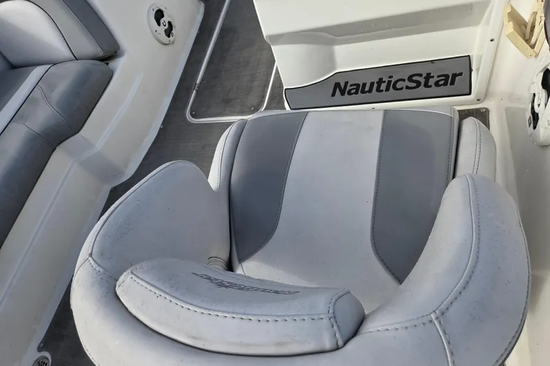 Slide: The Image of 2022 NauticStar 193 SC boat interior with gray seating and branding. - 10