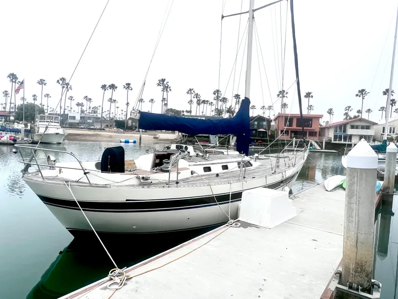 Slide: The Image of 1980 Lafitte 44 sailboat docked at marina with palm trees in background. - 1