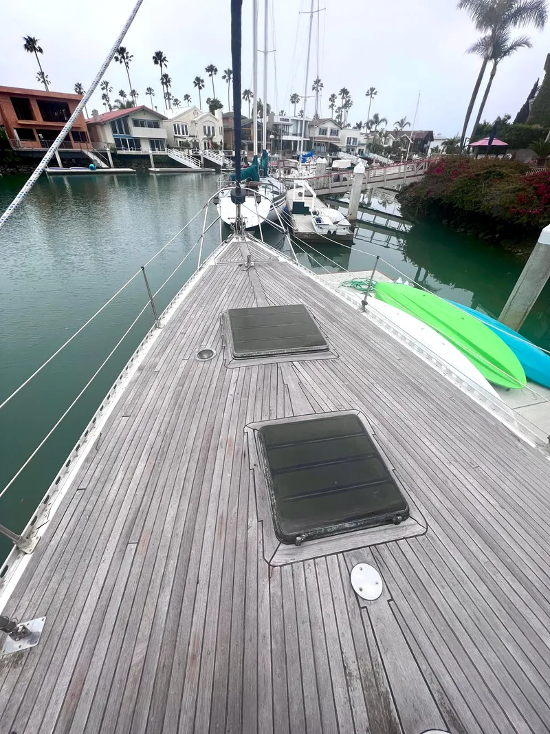 Slide: The Image of 1980 Lafitte 44 sailboat docked in a marina with palm trees and waterfront homes. - 11