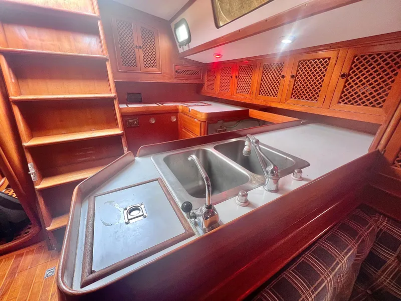 Slide: The Image of Interior of 1980 Lafitte 44 sailboat featuring a wooden kitchen with sink and cabinets. - 20