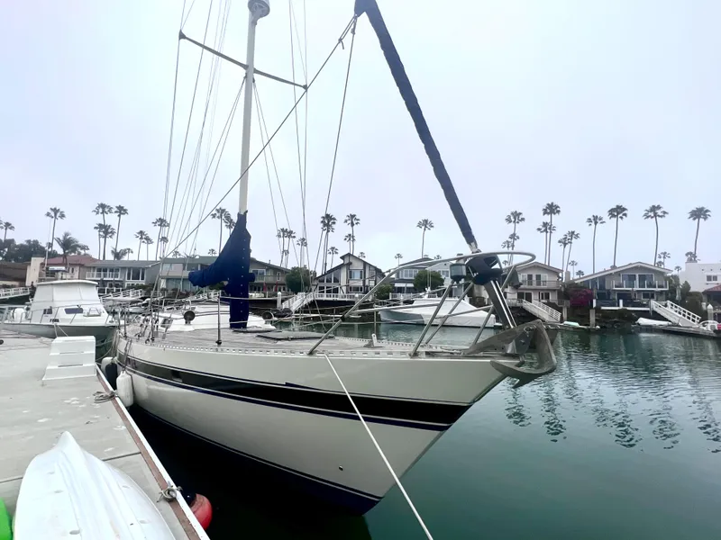 Slide: The Image of 1980 Lafitte 44 sailboat docked in a marina with palm trees in the background. - 7
