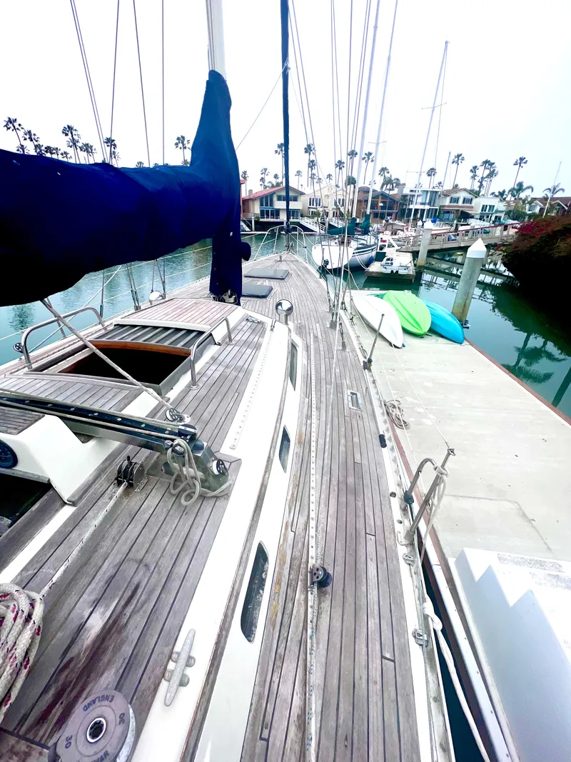 Slide: The Image of 1980 Lafitte 44 sailboat docked at marina with wooden deck and moored boats. - 9