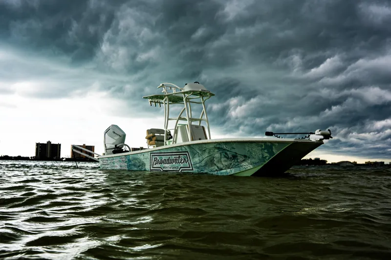 Slide: The Image of Broadwater Boatworks 25 Bay Cat 2026 on water under dramatic cloudy sky. - 18
