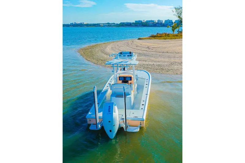 Slide: The Image of Broadwater Boatworks 2026 25 Bay Cat on serene coastal waters near sandy shore. - 2