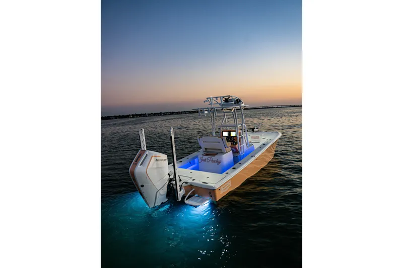 Slide: The Image of 2026 Broadwater Boatworks 25 Bay Cat at sunset with illuminated deck and powerful outboard motor. - 23
