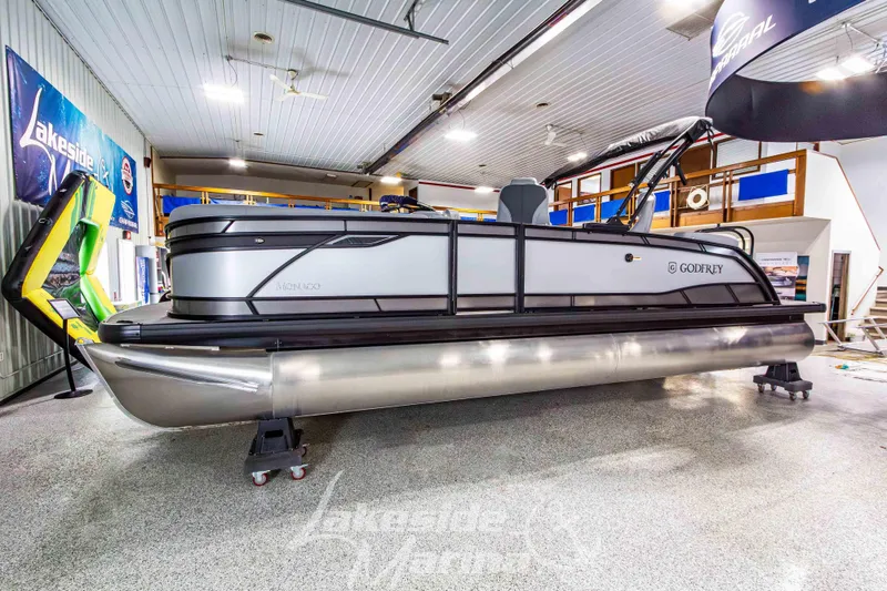 The Image of 2026 Godfrey Monaco 235 QSB pontoon boat displayed indoors at a showroom. - 1