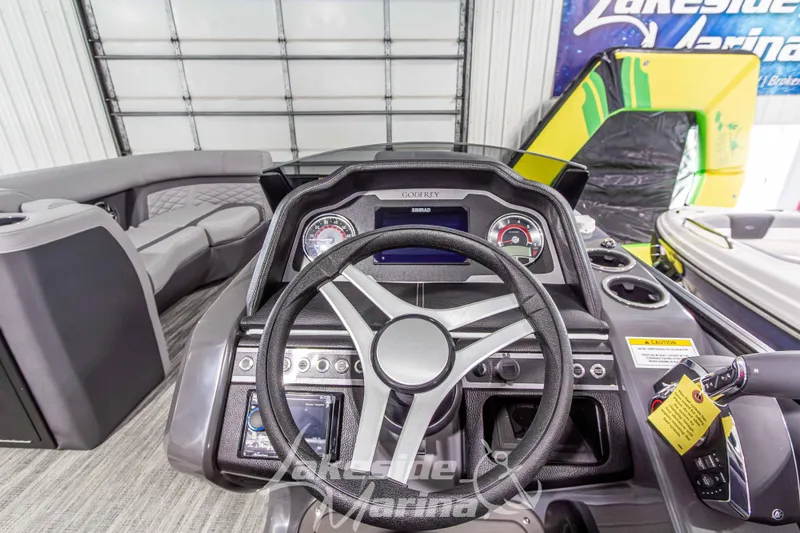 Slide: The Image of 2026 Godfrey Monaco 235 QSB boat dashboard with steering wheel and controls in showroom. - 34