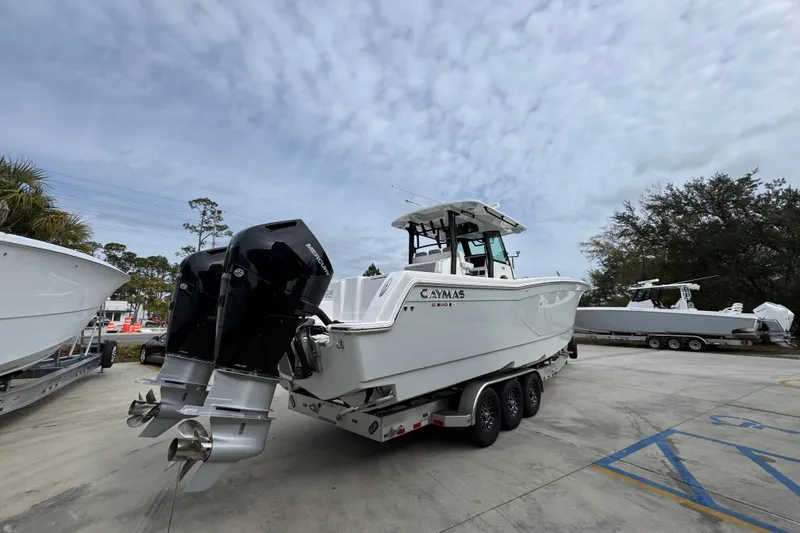 Slide: The Image of 2024 Caymas 34 CT boat with dual outboard motors on a trailer, under a cloudy sky. - 14