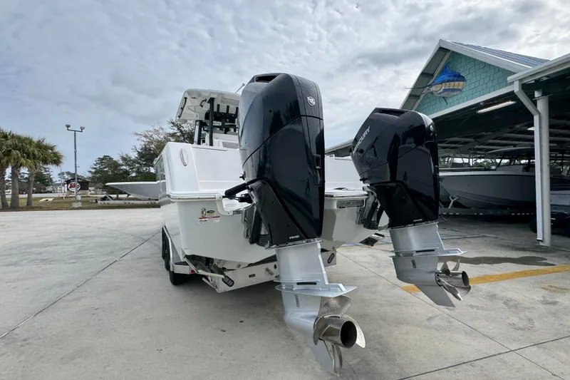 Slide: The Image of 2024 Caymas 34 CT boat with dual outboard engines, parked outdoors under cloudy skies. - 17