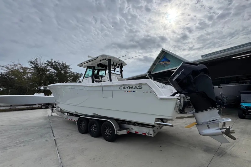 Slide: The Image of 2024 Caymas 34 CT boat on trailer, overcast sky, Mercury engine visible. - 19