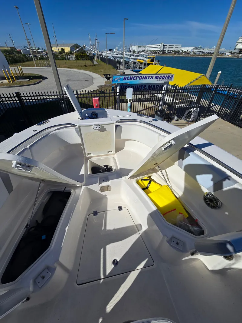 Slide: The Image of 2022 Robalo R272 Center Console at marina, open storage compartments visible. - 13