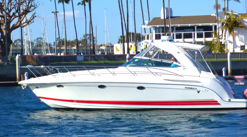 The Image of 2003 Formula 37 PC yacht cruising near marina with palm trees and waterfront buildings. - 0
