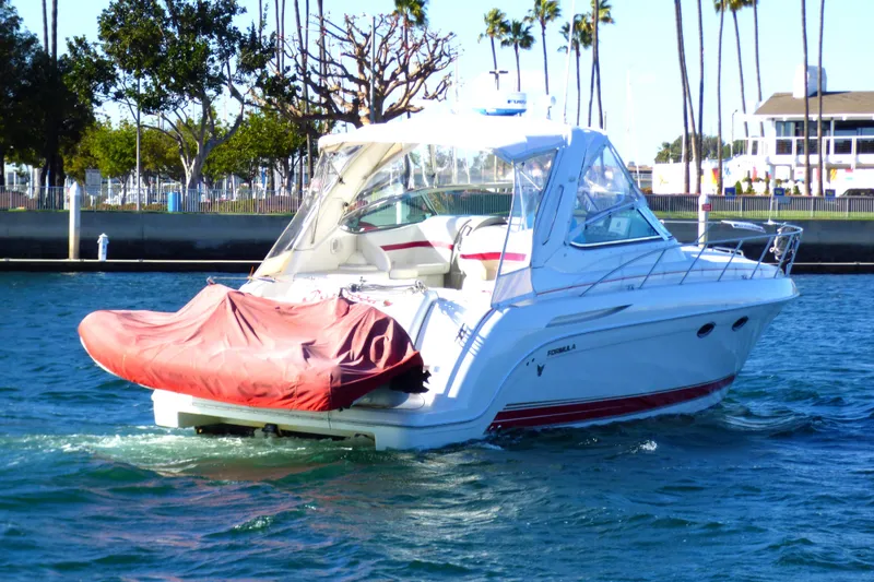 Slide: The Image of 2003 Formula 37 Performance Cruiser on water, with red cover, palm trees in background. - 2