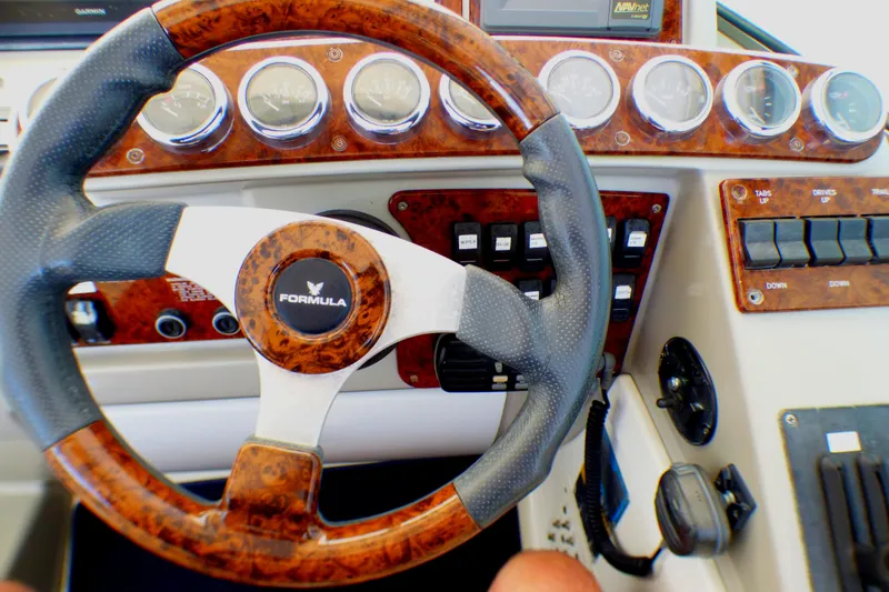 Slide: The Image of Steering wheel and dashboard of a 2003 Formula 37 PC boat, featuring wood accents and gauges. - 41