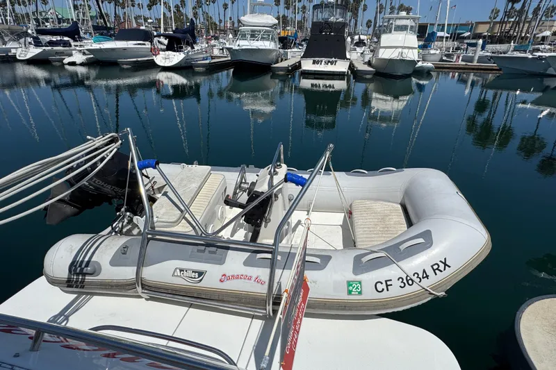 Slide: The Image of Inflatable boat docked at marina, surrounded by various yachts and clear blue water. - 59