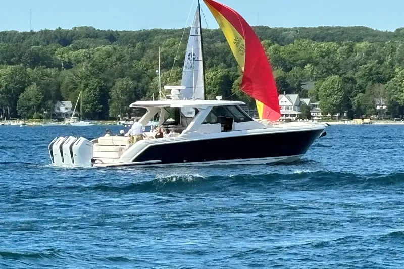 The Image of 2024 Tiara Yachts 48 LS cruising on a lake with vibrant sail and scenic background. - 0