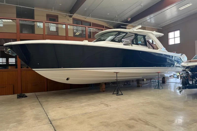 Slide: The Image of 2024 Tiara Yachts 48 LS in showroom, sleek design, blue and white exterior. - 51