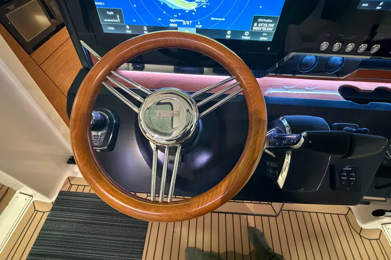 Slide: The Image of 2024 Tiara Yachts 48 LS helm with wooden steering wheel and navigation display. - 15