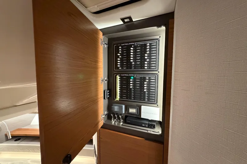 Slide: The Image of Electrical panel inside 2024 Tiara Yachts 48 LS, showcasing control systems and storage. - 19