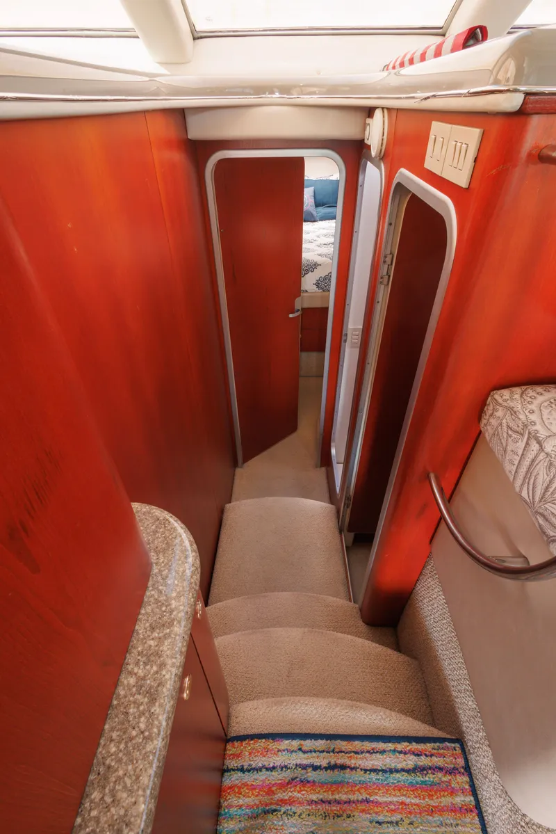 Slide: The Image of Interior of 1997 Maxum 4600 SCB yacht, featuring a narrow hallway and carpeted stairs. - 26