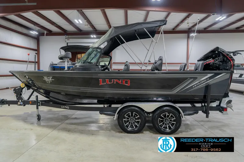 Slide: The Image of 2026 Lund 1975 Pro-V Sport boat in showroom with trailer and canopy. - 12