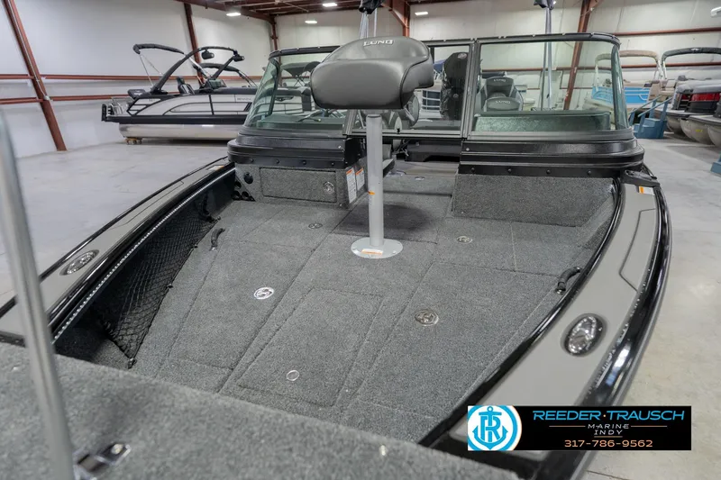 Slide: The Image of 2026 Lund 1975 Pro-V Sport boat interior with seating and carpeted deck in showroom. - 13