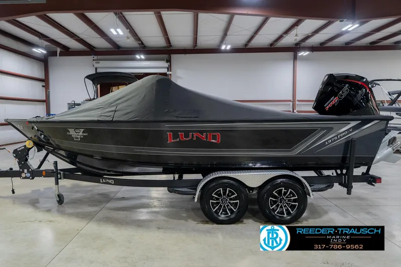 Slide: The Image of 2026 Lund 1975 Pro-V Sport boat with cover in a showroom, on a trailer. - 64