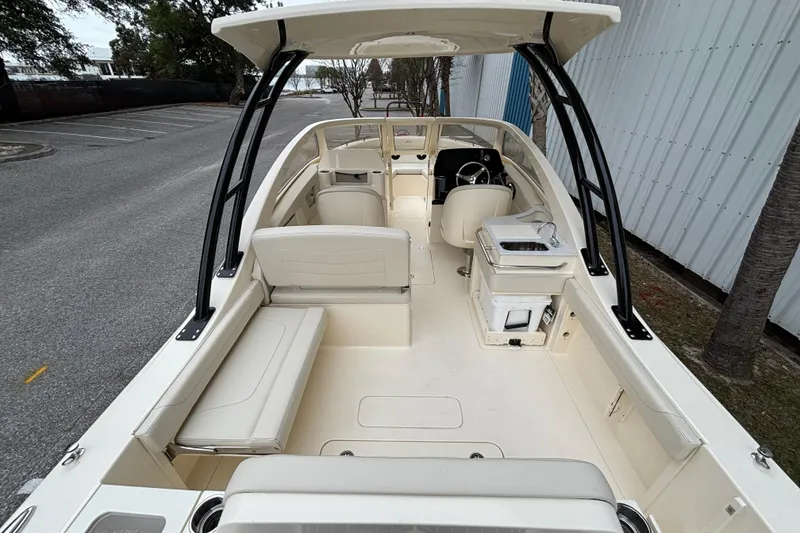 Slide: The Image of 2026 Scout 240 Dorado boat interior with seating and helm, parked near a building. - 12