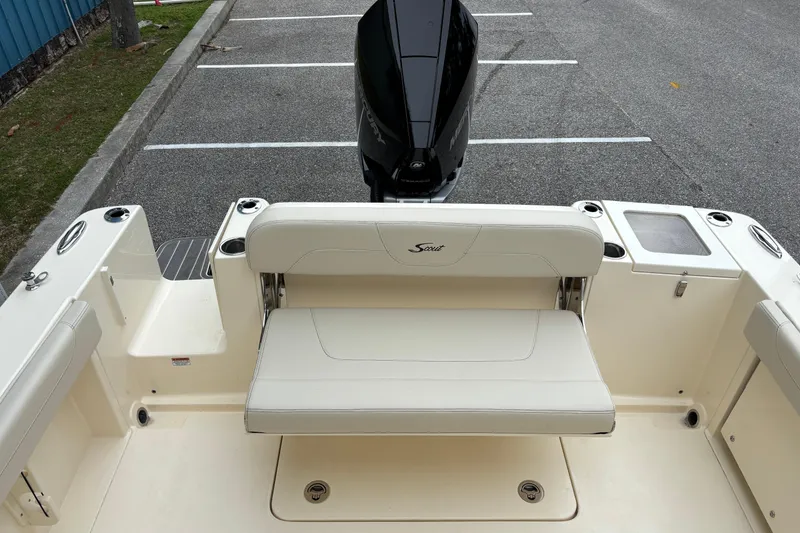 Slide: The Image of 2026 Scout 240 Dorado boat interior with seating and motor, parked in a lot. - 15