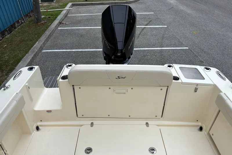 Slide: The Image of 2026 Scout 240 Dorado boat interior with seating and outboard motor in parking lot. - 16