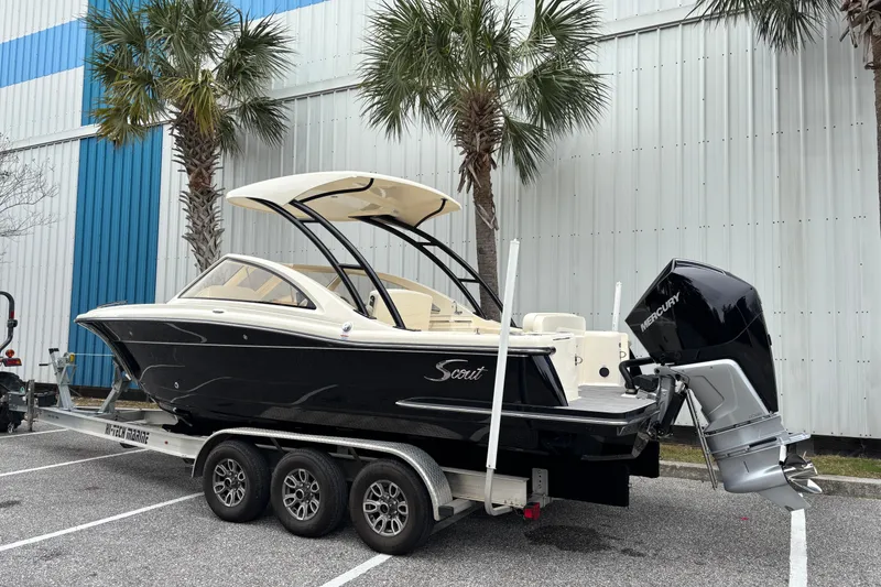 Slide: The Image of 2026 Scout 240 Dorado boat on trailer, parked near palm trees and a building. - 8