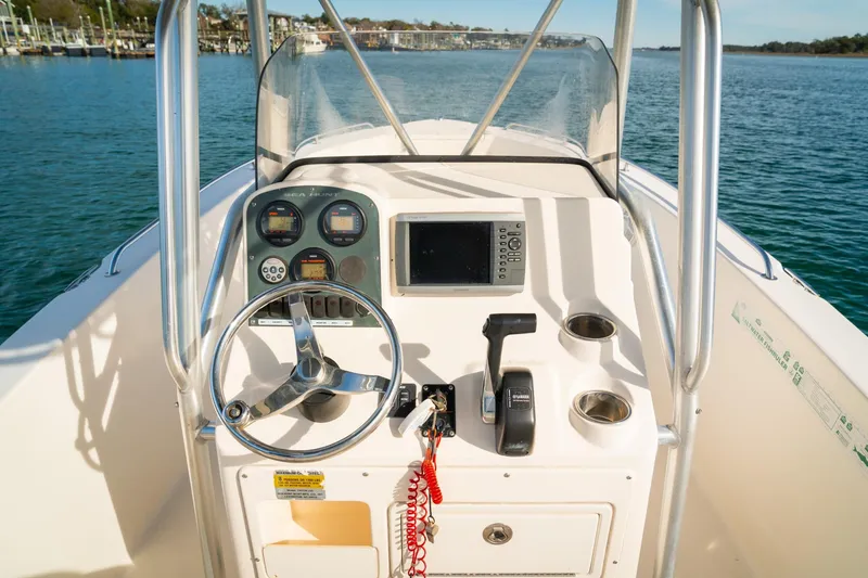 Slide: The Image of 2005 Sea Hunt Triton 232 boat console with steering wheel and navigation controls. - 13