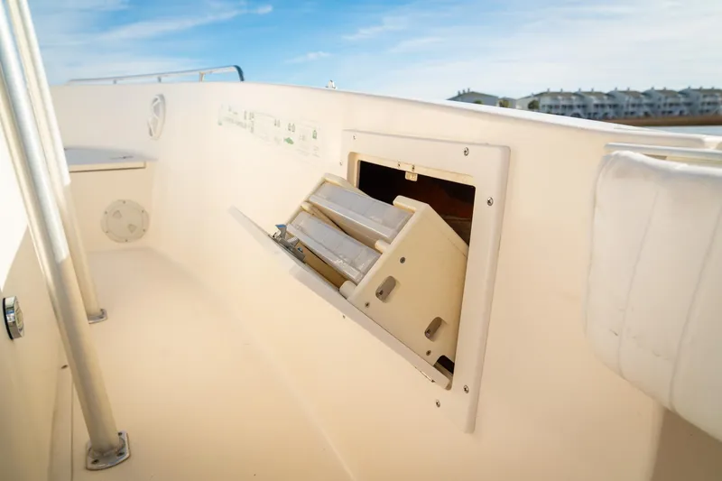Slide: The Image of 2005 Sea Hunt Triton 232 boat interior with open storage compartment, sunny day. - 18