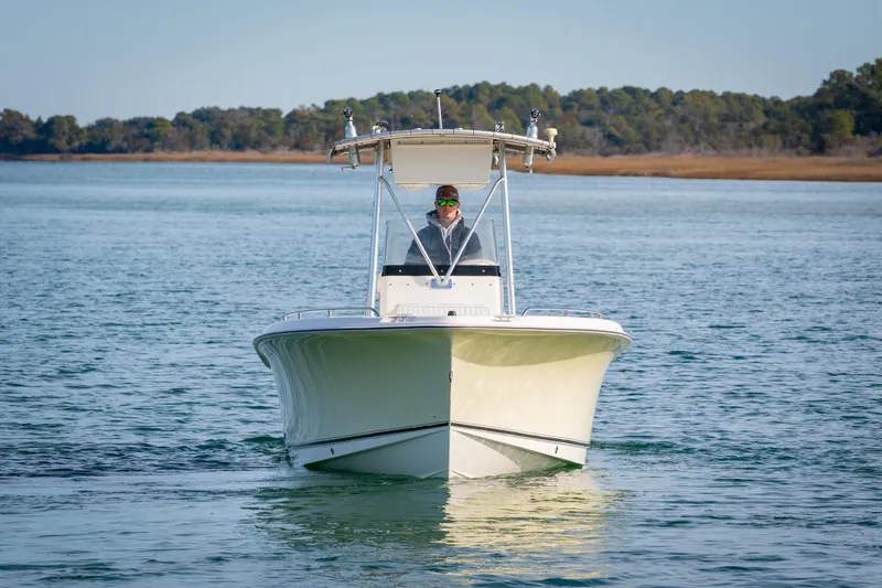 Slide: The Image of 2005 Sea Hunt Triton 232 boat cruising on calm water with a person at the helm. - 2