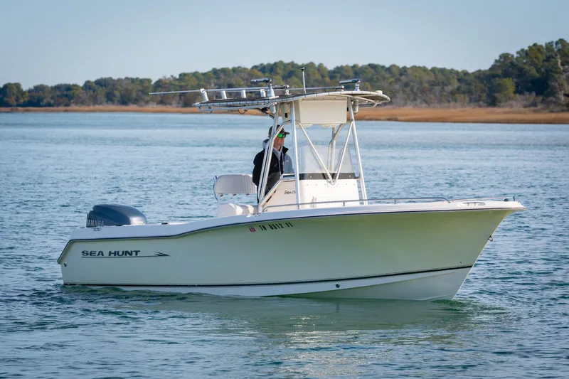Slide: The Image of 2005 Sea Hunt Triton 232 boat on calm water with scenic background. - 3