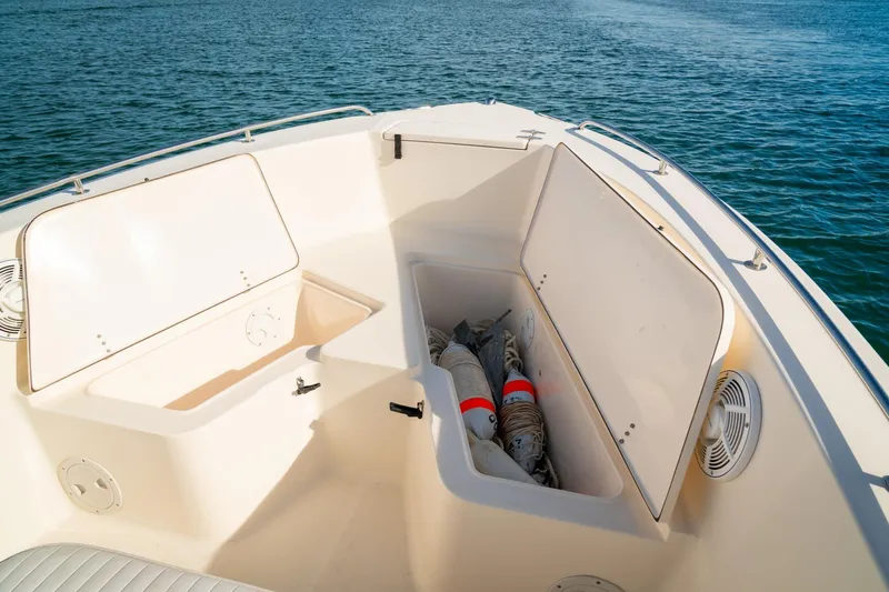 Slide: The Image of 2005 Sea Hunt Triton 232 boat storage compartments open on calm water. - 9