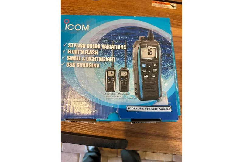 Slide: The Image of Box of Icom IC-M25 marine radio with features listed, on wooden surface. - 23
