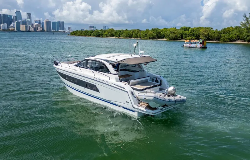 Slide: The Image of 2019 Jeanneau Leader 40 yacht cruising near a city skyline and lush greenery. - 18